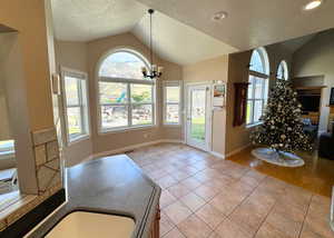 Foyer entrance featuring a textured ceiling, a chandelier, light tile patterned flooring, and lofted ceiling