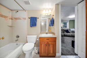 Bathroom with vanity, a textured ceiling, shower / tub combination, light tile patterned floors, and light colored carpet