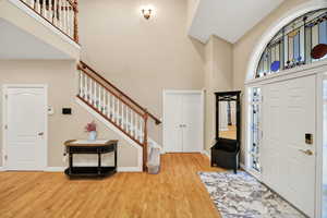 Foyer entrance featuring wood finished floors, a towering ceiling, and stairway