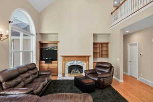 Living room featuring light wood finished floors, a premium fireplace, and high vaulted ceiling