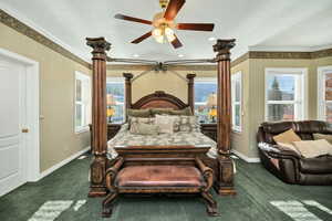 Primary Bedroom with dark carpet, ornamental molding, and ceiling fan