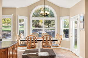 Dining room featuring plenty of natural light, light tile patterned floors, a chandelier, and a water view