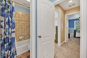 Full bathroom with shower / bathtub combination with curtain, a ceiling fan, carpet floors, and tile patterned flooring