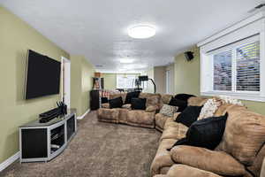 Carpeted living area with a textured ceiling and baseboards