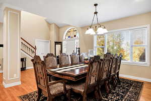 Dining space featuring light wood finished floors, a chandelier, and stairs