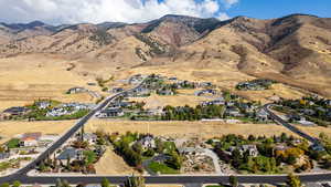 Aerial view of property and surrounding area featuring a mountainous background and nearby suburban area