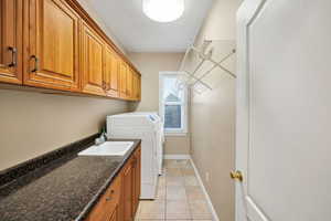 Laundry area featuring light tile patterned flooring, cabinet space, and washing machine and dryer