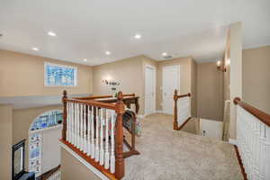 Hall with an upstairs landing, recessed lighting, and carpet flooring