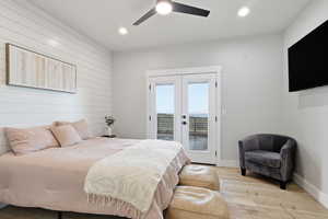MASTER: Bedroom with wood walls, light wood-style flooring, french doors, ceiling fan, and access to outside