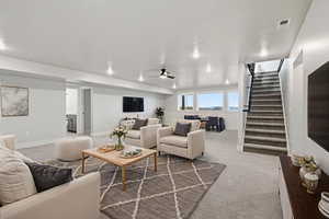 Virtual Staged: Living room featuring light carpet, stairway, and a ceiling fan
