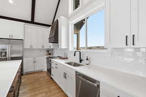 Kitchen with white cabinets, stainless steel appliances, tasteful backsplash, premium range hood, and light stone countertops