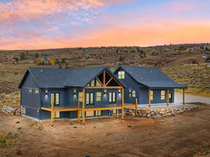 Back of house at dusk featuring a porch and a view of rural / pastoral area