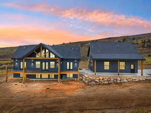 Back of house at dusk featuring roof with shingles