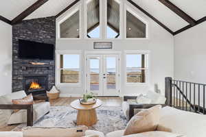 Living area with high 18' vaulted ceiling, LVP wood-style floors, a stone fireplace, and beamed ceiling and view