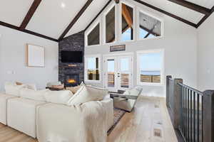 Living area with high 18' vaulted ceiling, LVP wood-style floors, a stone fireplace, and beamed ceiling