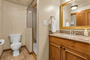 Full bath with vanity, light tile patterned flooring, a shower stall, and a textured wall