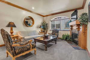 Living area featuring ornamental molding, carpet flooring, and a tiled fireplace