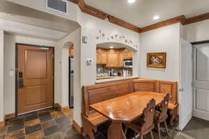 Dining room featuring ornamental molding, stone tile flooring, recessed lighting, and arched walkways