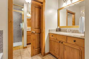 Bathroom with vanity, light tile patterned floors, and a shower stall