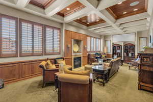 Living area with light colored carpet, coffered ceiling, beam ceiling, a wainscoted wall, and a tile fireplace