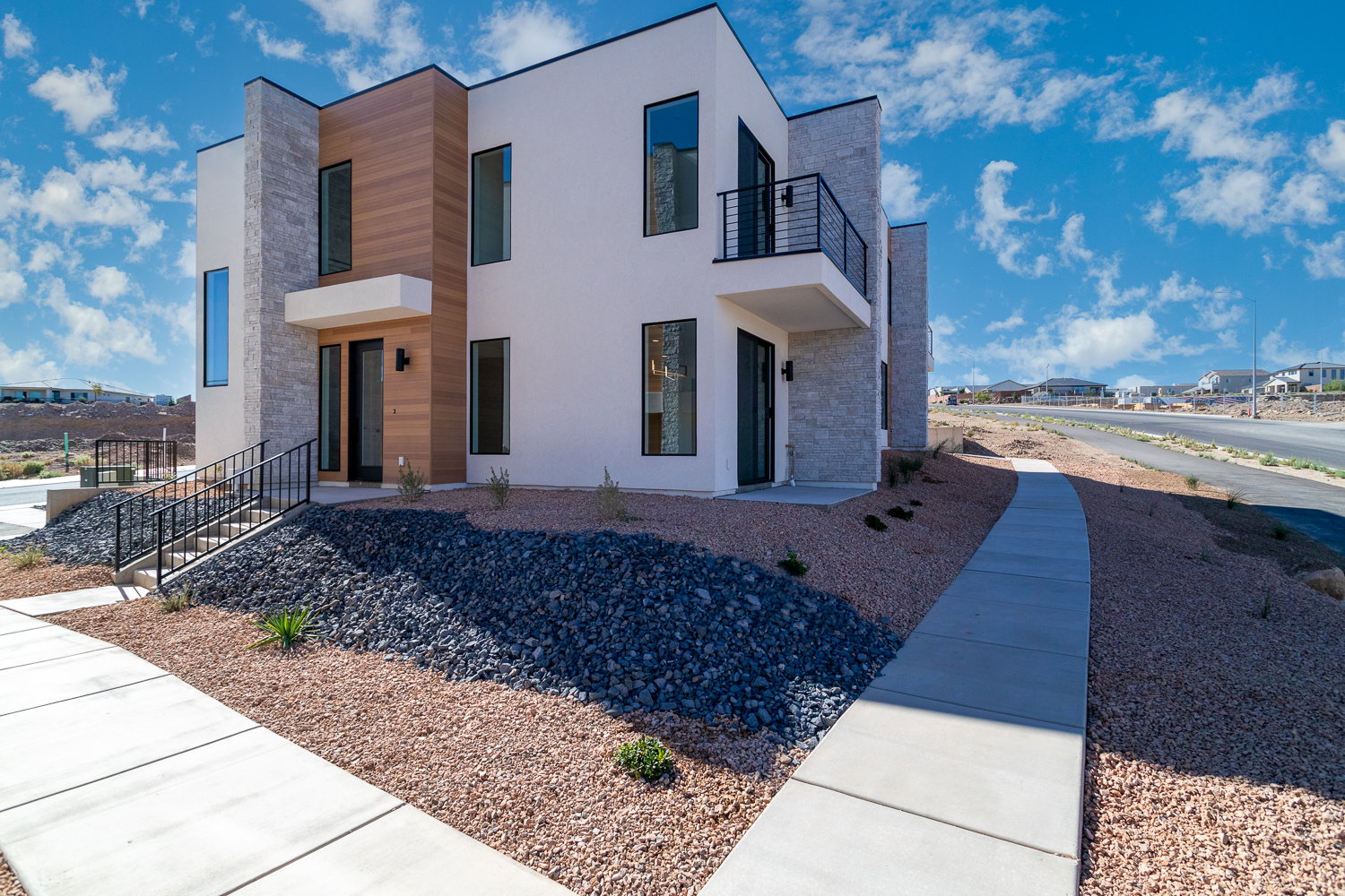 View of front facade with stone siding, stucco siding, a balcony, and a residential view