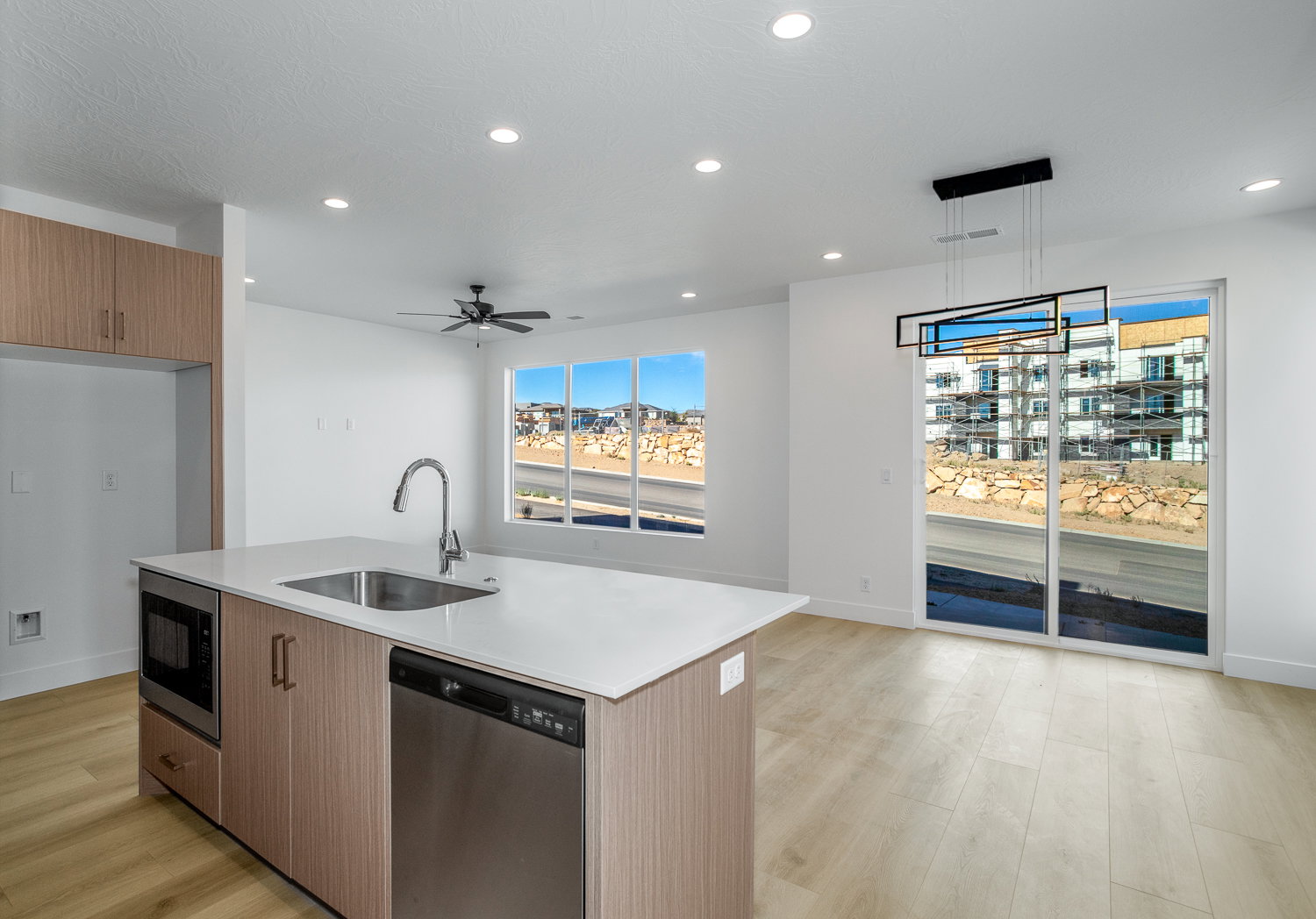 Kitchen featuring hanging light fixtures, stainless steel appliances, light wood finished floors, recessed lighting, and a kitchen island with sink