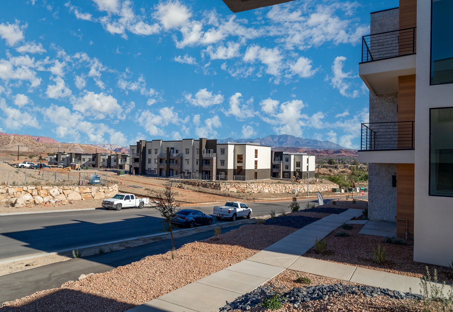 View of asphalt road featuring a mountain view, sidewalks, a residential view, and curbs