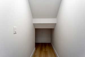 Hallway with light wood-style flooring and lofted ceiling
