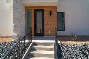 Property entrance with stucco siding, stone siding, and covered porch