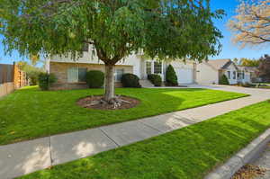 View of front facade with brick siding, driveway, and an attached garage