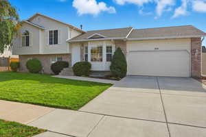 Tri-level home with brick siding, roof with shingles, concrete driveway, and an attached garage