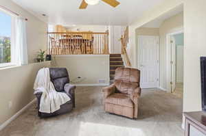 Sitting room featuring carpet, ceiling fan, and stairs