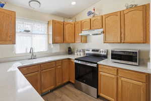 Kitchen featuring appliances with stainless steel finishes, light wood-style flooring, under cabinet range hood, recessed lighting, and light stone countertops