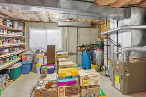 Unfinished basement with heating unit, a water pressure tank, and gas water heater