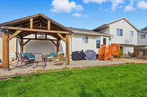 Back of house with a patio area, a lawn, a gazebo, and roof with shingles