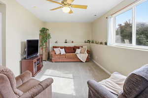 Living area featuring carpet floors and ceiling fan