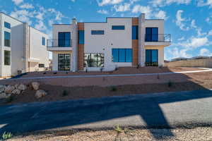 Back of house with stucco siding and a balcony