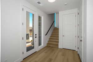 Doorway to outside featuring stairs and wood finished floors