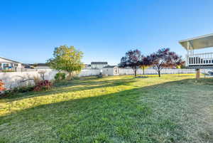 Fenced backyard featuring a storage shed