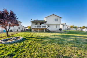 Back of property with a fenced backyard, a fire pit, and a  deck