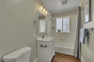 Bathroom with dark wood finished floors, vanity, and shower / bath combination with curtain