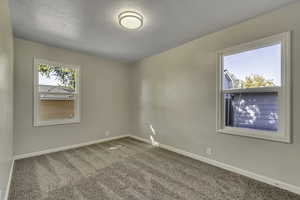 Carpeted empty room with baseboards and a textured ceiling