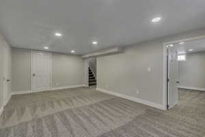 Below grade area with light colored carpet, recessed lighting, and stairs