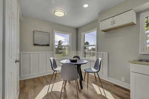 Dining space with light wood-type flooring, a wainscoted wall, and a decorative wall