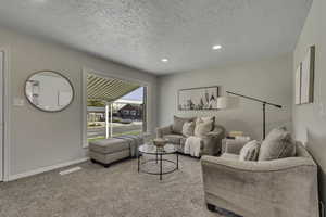Carpeted living room featuring a textured ceiling and recessed lighting