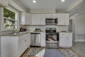 Kitchen with stainless steel appliances, white cabinetry, backsplash, recessed lighting, and light wood finished floors