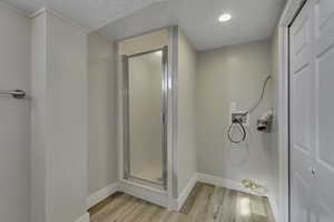 Full bath with light wood-style floors and a stall shower
