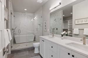 Bathroom featuring double vanity, a walk in closet, a marble finish shower, dark tile patterned floors, and recessed lighting