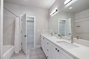 Bathroom featuring double vanity, a spacious closet, shower / tub combo, light tile patterned floors, and recessed lighting