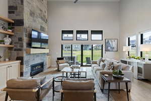 Living area with a fireplace, light wood-style flooring, and a high ceiling